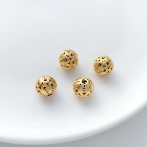 Detailed macro of four gold hollowed-out floral round beads for DIY jewelry making