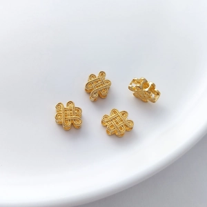 Close-up of four golden Chinese knot spacer beads for DIY jewelry making accessories