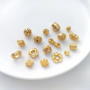 Detailed macro view of gold-plated lotus and Chinese knot charms on white ceramic tray
