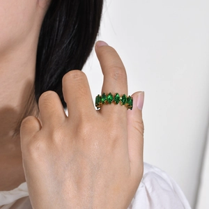 Detail of gold band ring with marquise-cut green zircon stones worn on finger