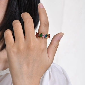 Close-up of a gold ring with multi-colored marquise-cut zircons worn on a finger