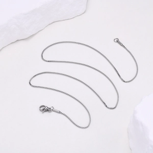 Détail d'une chaîne box argentée de 2mm avec fermoir homard sur une pierre blanche