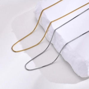 Détail de colliers chaîne box 2mm en finitions or et argent sur fond de marbre