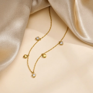 Detail view of gold heart necklace with zircon stones on premium champagne silk fabric