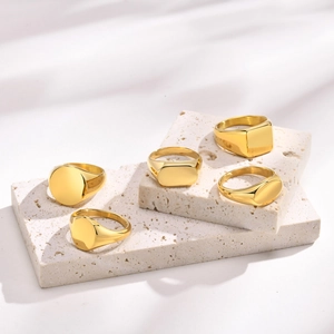Polished gold stainless steel signet rings in geometric shapes on stone pedestals