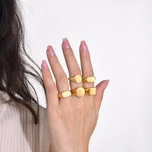 Detailed view of five gold polished geometric signet rings worn on a hand over white background
