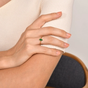 Gros plan sur une bague minimaliste en or avec zircon émeraude sur main de femme