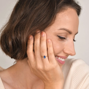 Bague fine en or avec saphir taille marquise, présentée sur la main d'un mannequin