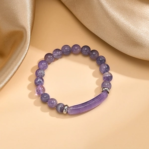 Dettaglio del bracciale con perline di ametista e barra curva viola su seta