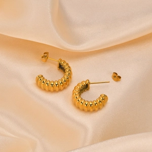 Elegant gold-plated C-shape striped hoop earrings on champagne silk fabric background