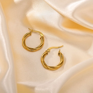 Elegant gold twisted hoop earrings in stainless steel displayed on champagne silk fabric