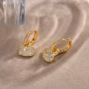 Elegant gold heart earrings with pavé set cubic zirconia on warm velvet background