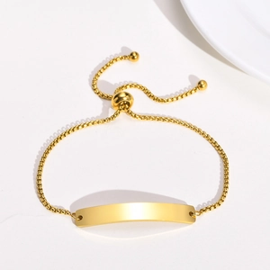 Detail of adjustable gold stainless steel bracelet with engravable curved bar and bead