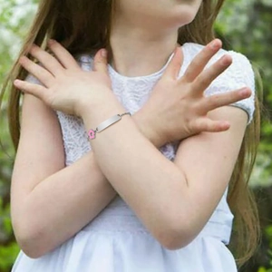 Detailed view of child's pink flower charm bracelet with engravable stainless steel plate