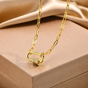 Detail of gold necklace with pavé zircon carabiner pendant on a velvet background