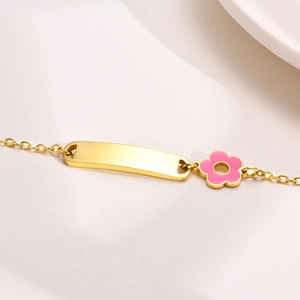 Detail of pink floral charm and polished metal ID plate on a gold-plated steel bracelet