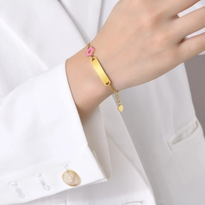 Gold stainless steel bracelet with pink flower, curved bar, and heart pendant on wrist