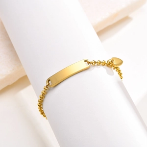 Minimalist gold ID bracelet with customizable bar and heart charm on white marble background