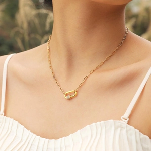 Golden paperclip chain necklace with a zircon-encrusted lock pendant worn by a model