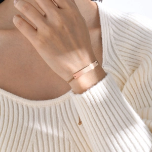 Close-up of a polished rose gold stainless steel bar bracelet worn on a female wrist