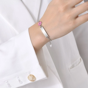 Detailed macro of a women's stainless steel bracelet with a pink flower and engravable plate