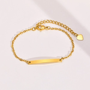 Detailed close-up of golden stainless steel chain bracelet with blank curved plate and heart charm
