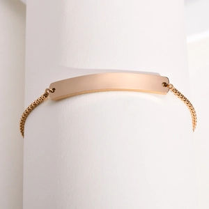 Detail of a rose gold curved bar bracelet on a stand for custom DIY engraving