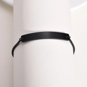 Close-up of minimalist black matte stainless steel ID bracelet on a white display stand