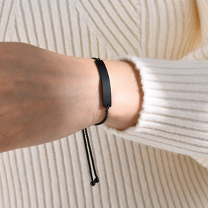 Close-up of matte black adjustable bracelet with customizable nameplate on a model