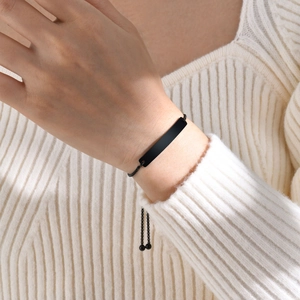 Adjustable black stainless steel ID bracelet on wrist over a white knit sweater