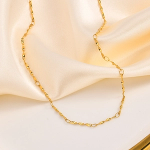 Elegante Halskette aus Gold-Titanstahl mit gedrehten Wellen auf weißem Seidenhintergrund