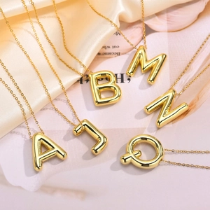 Minimalist gold bubble initial pendant necklace set on champagne satin background
