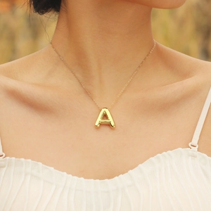 Detailed view of 18K gold plated letter A pendant necklace worn by a female model