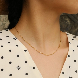 Detail einer 18K vergoldeten Edelstahl-Spiralkette am Hals eines weiblichen Models
