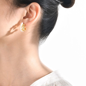 Détail de boucles d'oreilles dorées en C avec perles sur mannequin, style élégant