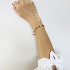 Detail of minimalist 5mm rose gold stainless steel bangle with a matte brushed finish