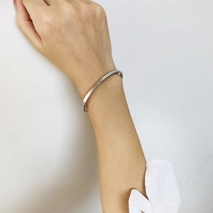 Close-up of a minimalist silver stainless steel cuff bangle worn on a model's wrist