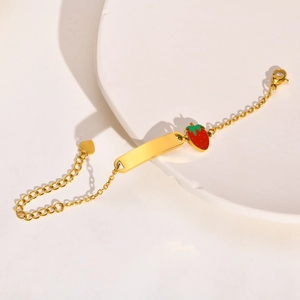 Detail of gold-plated stainless steel baby ID bracelet with red strawberry enamel charm