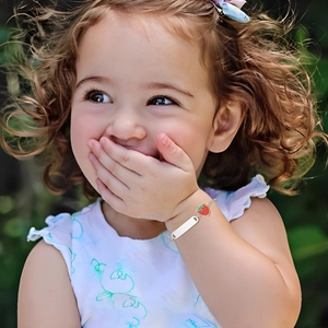 Close-up of a smiling child wearing a strawberry charm bracelet with custom silver nameplate