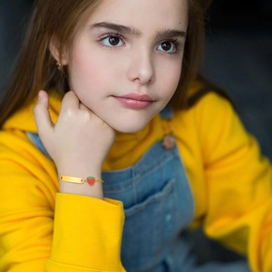 Close-up of a child wearing a gold strawberry bracelet with an engravable ID plate