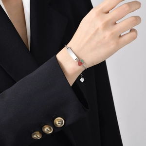 Detail of stainless steel ID bracelet featuring a red strawberry charm and engraving plate