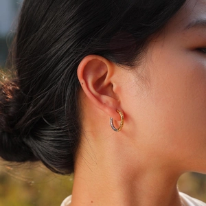 Close-up of a model wearing two-tone gold and silver faceted stainless steel hoop earrings