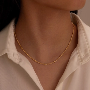 Minimalist gold stainless steel beaded cable chain necklace on a white shirt model