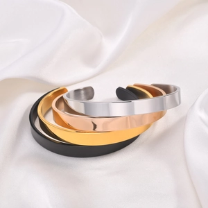 Detailed view of four C-shaped stainless steel cuffs in silver, gold, rose gold and black