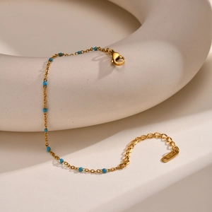 Close-up of 18K gold chain bracelet with blue beads and K18 hallmark tag details