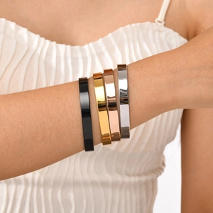 Close-up of four polished stainless steel C-shaped open bangles in multi-color finishes