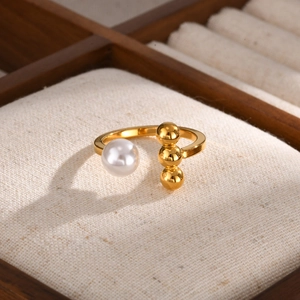 Macro detail van vergulde open ring met witte parel en drie verticale metalen kralen