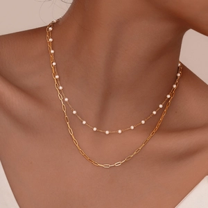 Gros plan sur le collier double rang doré avec chaîne trombone et perles blanches