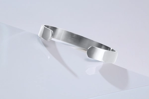 Close-up of a wide silver stainless steel cuff bracelet with smooth polished finish