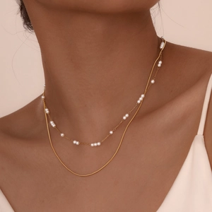 Double layered gold snake chain necklace with faux pearls for women on model neck
